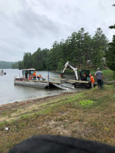 UPL Electrical team members unloading an electrical pole from a boat